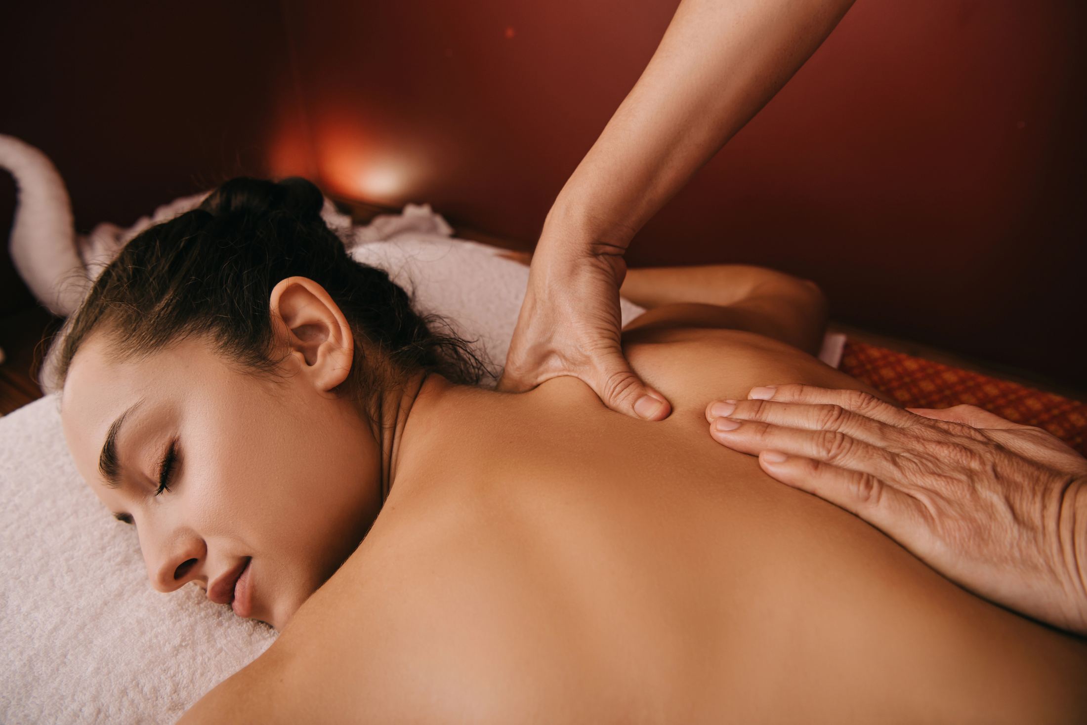 Close-up of a holistic back massage in progress, candlelit treatment room